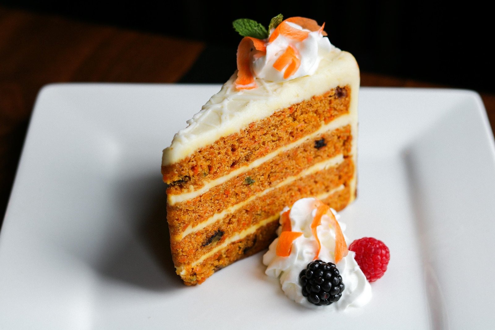 Carrot cake slice with cream cheese frosting, fresh blackberry, raspberry, and mint at Tequila Fuego Longview