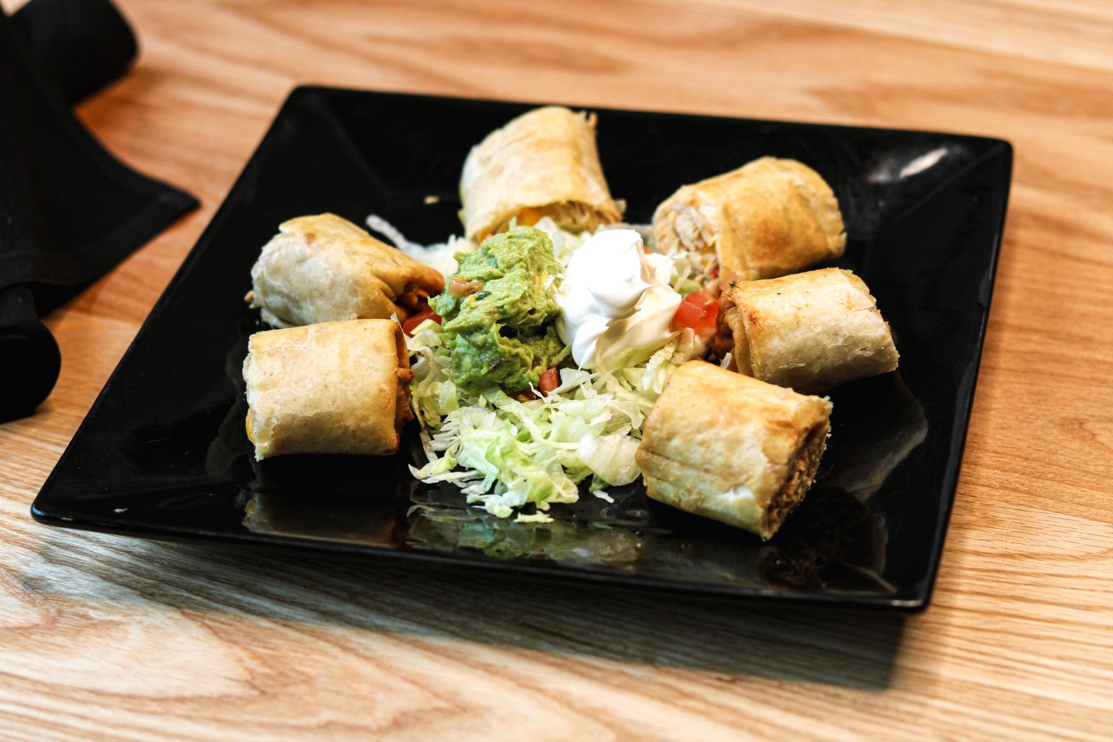 Crispy rolled chicken taquitos topped with guacamole and sour cream, Tequila Fuego happy hour Longview.