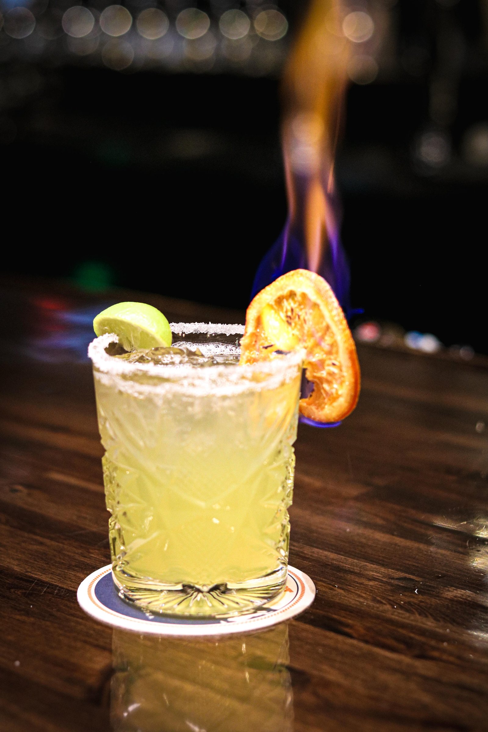 Classic margarita in a salted glass with lime and flaming orange slice garnish, Tequila Fuego happy hour Longview WA.