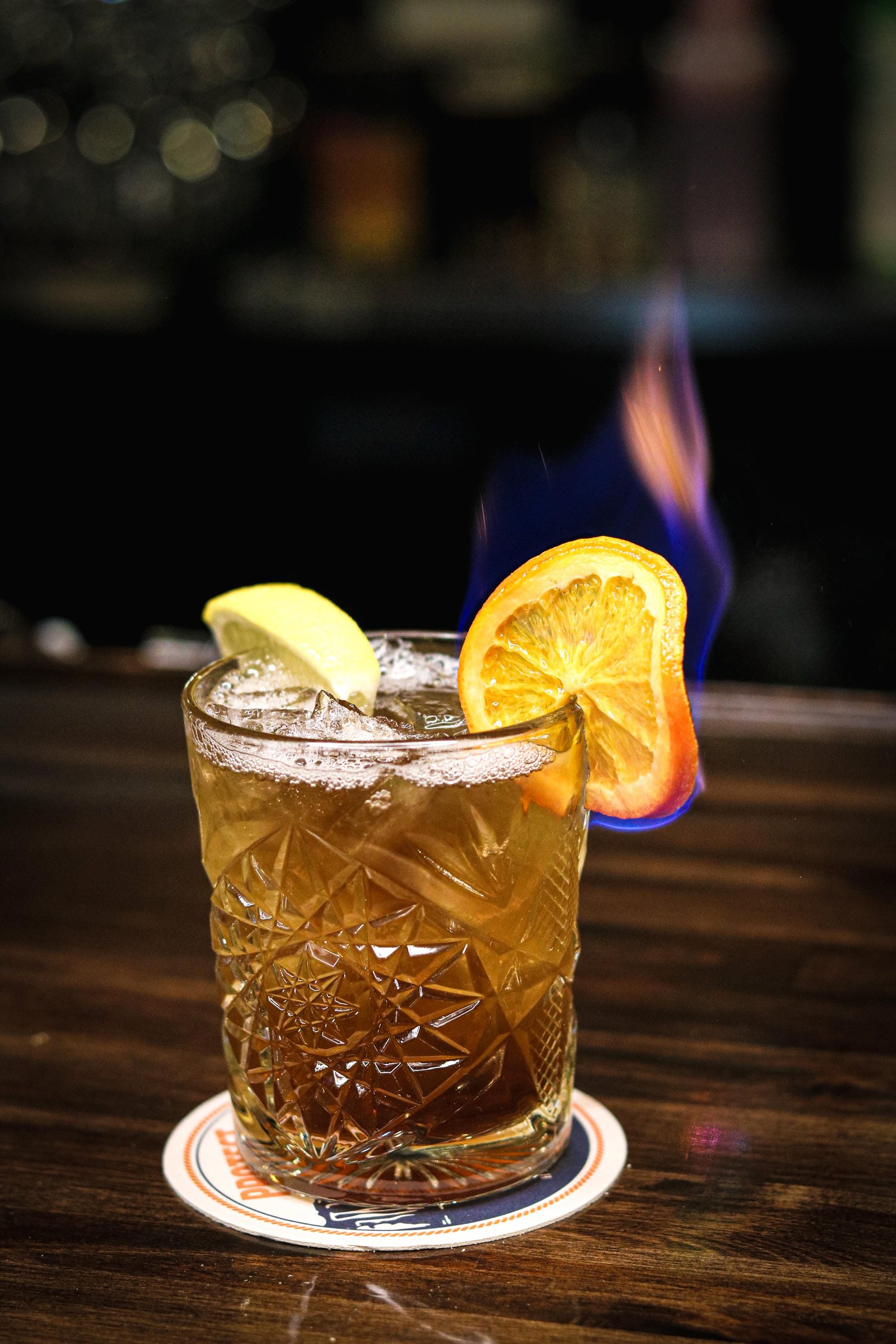 Long Island iced tea style cocktail with lime and flaming orange garnish, Tequila Fuego happy hour Longview.