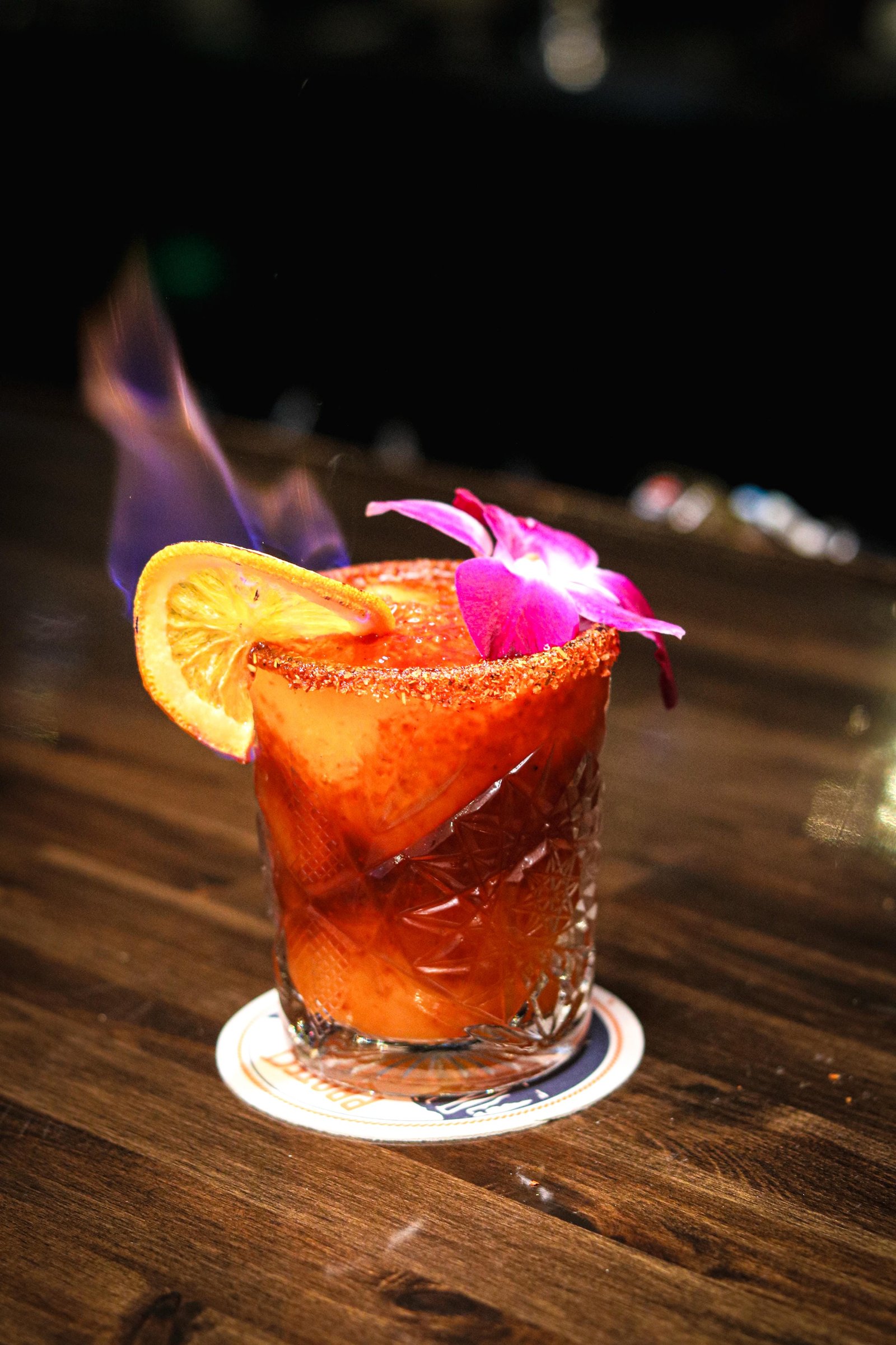 Mangonada margarita with chili-salt rim, orchid, and flaming orange slice, Tequila Fuego happy hour Longview WA.